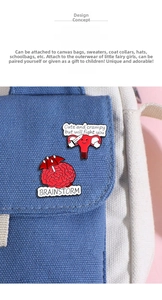 Detail von kreativen Zeichentrick-Hirn- und Uterus-Emaille-Pins auf blauem Leinenbeutel