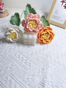 Close-up of hand-knitted crochet peony flowers in pink and orange on a white stand