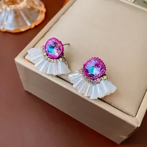 Eleganti orecchini a ventaglio con cristallo viola e strass su una scatola per gioielli