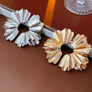 Macro shot of gold and silver pleated fan-shaped earrings with artistic metal textures