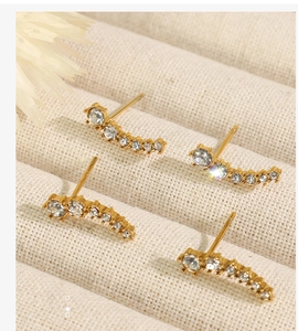 Macro shot of gold crescent stud earrings featuring a gradient of sparkling white zircons