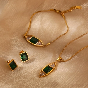 Ensemble détaillé de bijoux en émeraude sur fond de tissu doré luxueux et élégant