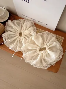 Close-up of cream bow scrunchies with delicate lace edges and textured fabric