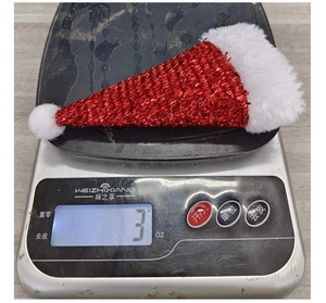 Mini Christmas hat decor featuring red sequins and white plush trim shown on a scale