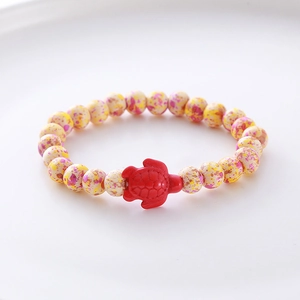 Detailed close-up of beaded bracelet with spotted yellow beads and a red turtle charm