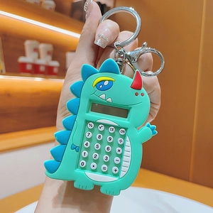 Close-up of a green cartoon dinosaur mini calculator keychain being held by hand