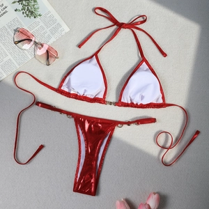 Flat lay of red shiny metallic bikini with pearl details and stylish vacation accessories