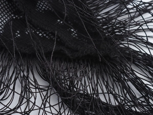 Close-up detail of black mesh knit fabric with long fringe tassels for Y2K style evening dress