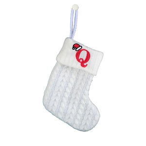 Close-up of a white knit Christmas stocking featuring a red embroidered letter Q on the cuff
