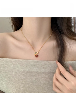 Detail of red heart pendant necklace on model's neck with 18k gold plating