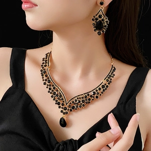 Detail of V-shaped gold necklace and earrings set with vintage black teardrop gemstones