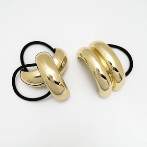 Close-up detail of glossy golden alloy hair ties with black elastic bands