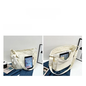 Detail of large capacity white canvas bag with bear charm and internal compartments