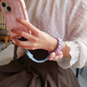 Pink and blue woven phone wrist strap with fabric flower accessory for women