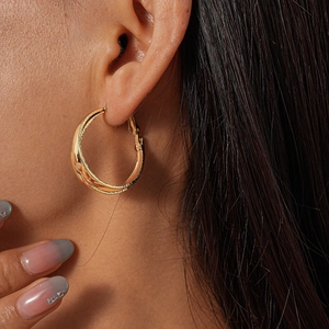Close-up of golden hollow layered hoop earrings with textured finish on female model