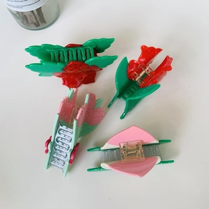 Dettaglio di quattro mollette per capelli a forma di rosa e tulipano in vari colori vivaci