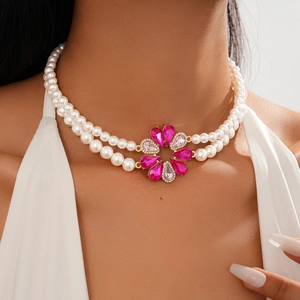 Detail of a double-layer pearl necklace with a pink crystal floral pendant on a model