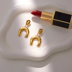 Boucles d'oreilles fer à cheval en forme de U dorées martelées sur plateau blanc