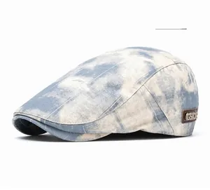 Detail of grey blue tie-dye flat cap featuring a GSTOR vintage leather brand tag
