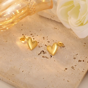 Polished 18k gold plated heart stud earrings on a minimalist marble decorative background