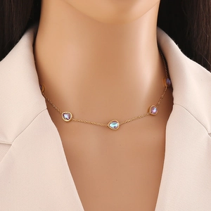 Collana dorata con pietre camaleonte a forma di pera indossata su un blazer beige