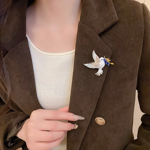 Close-up of a peace dove brooch with blue crystals on a brown corduroy blazer lapel