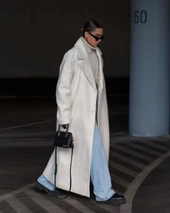 Gros plan sur la texture pelucheuse et le col à revers du manteau long pour femme ivoire