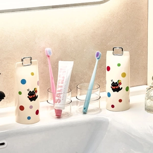 Gobelets brosse à dents beiges avec motifs de chats noirs dans une salle de bain