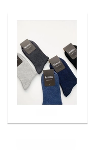 Close-up of four pairs of ribbed combed cotton socks in grey, navy blue, and black colors