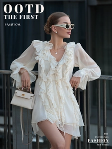 Detail of white chiffon dress featuring layered ruffles, V-neck, and long lantern sleeves