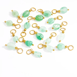 Detailed macro view of light green natural stone charms with golden hoops for jewelry making