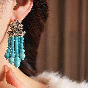 Details von Vintage-Ohrringen im Boho-Stil mit Türkisperlen und glänzenden Strassbesätzen