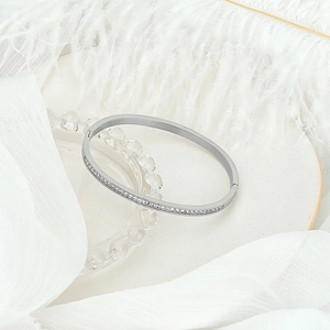 Detail shot of silver bangle with pavé zircons on white feather and silk backdrop