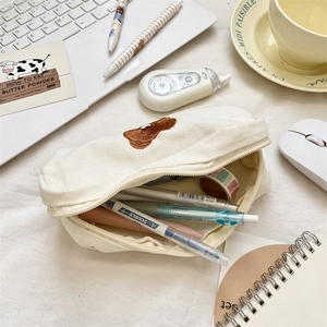 Detail of cute bear embroidery on a beige canvas pencil case with desktop stationery