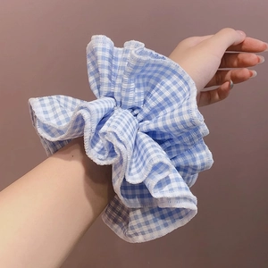Blue and white gingham checkered ruffle scrunchie worn on a model's wrist for styling