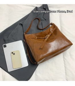 Detailed size comparison of the brown oil-wax leather tote bag with a phone and iPad