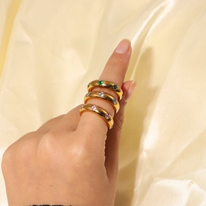 Close-up of vintage gold rings set with green, white, and pink cubic zirconia gems