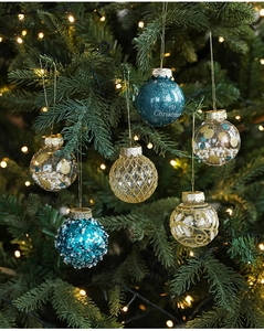Detailed view of blue and gold Christmas balls with festive text hanging on tree