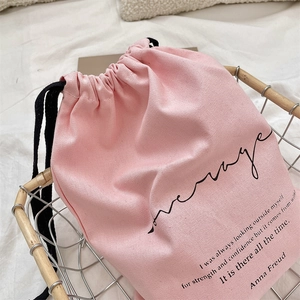 Detailed close-up of pink linen drawstring bag with Anna Freud quote in a storage basket