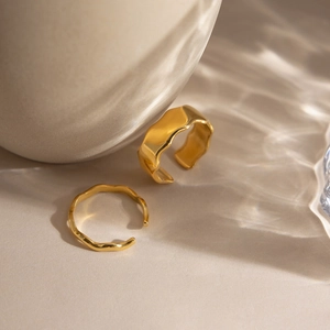 Detailed view of wave-textured 18K gold stainless steel open rings with water ripple shadows