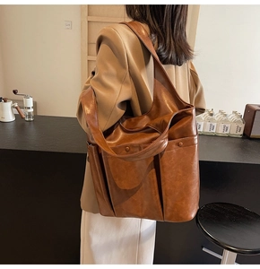 Side view of a large brown PU leather tote bag featuring wide straps and spacious pockets