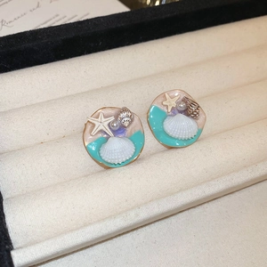 Macro detail of vintage starfish and shell earrings with pearls in Tiffany blue and gold