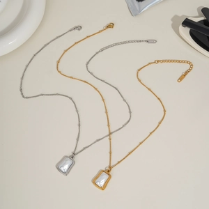 Détail de colliers avec pendentif perle dorés et argentés sur un fond lifestyle