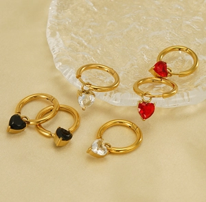 Detail of heart-shaped zircon charms on golden stainless steel hoop earrings