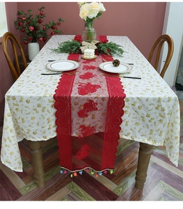 Detailed close-up of red lace Christmas table runner with festive patterns and colorful tassels