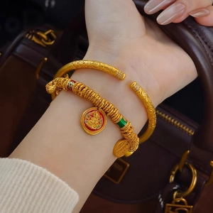 Macro shot of 24k gold plated bangle with zircon stones and red enamel charm