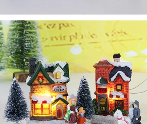 Detail of LED glowing Christmas resin house with snow-covered trees and miniature figures