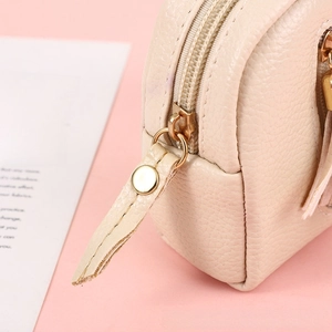 Close-up of cream pebble leather coin purse showing gold zipper detail and fine texture