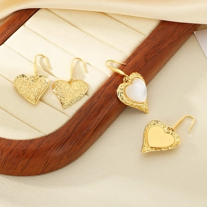 Detailed view of gold heart earrings set with hammered texture and cat eye stone inlays