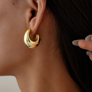 Close-up of model wearing large polished gold C-shape drop stud earring for women